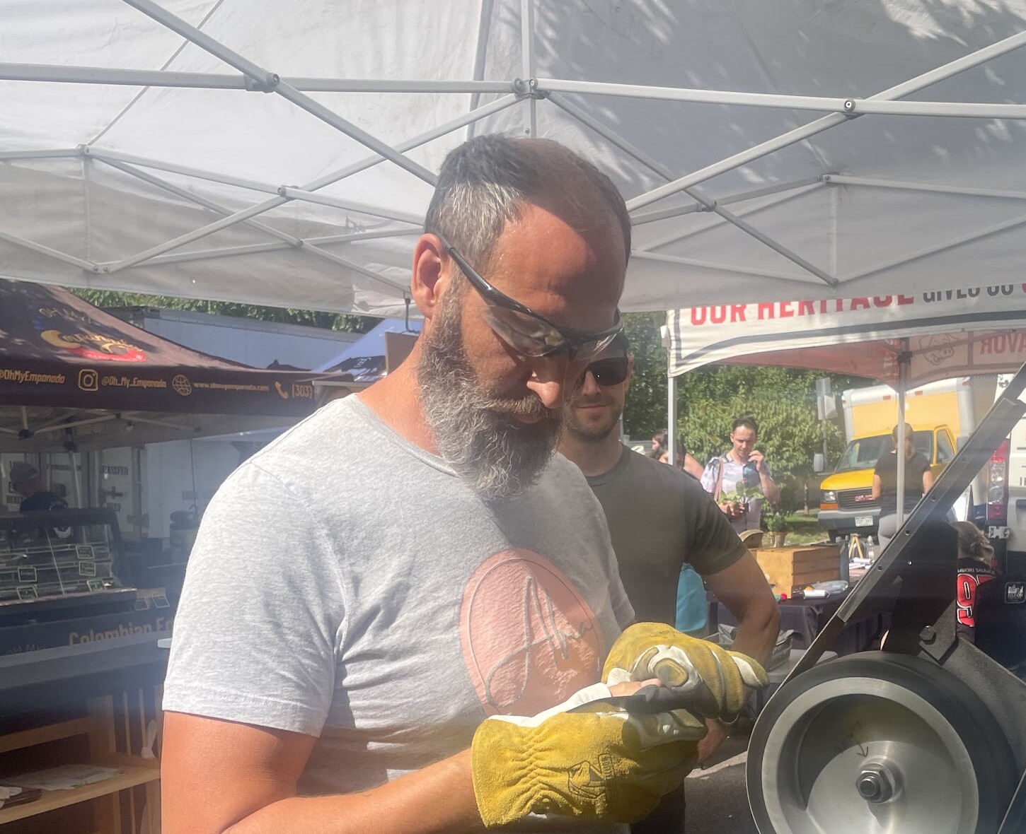 Erik sharpening a blade at the Afia CO Sharpening market booth